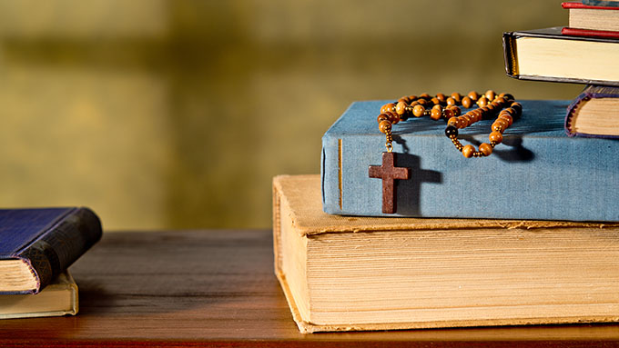 Rosary and books stacked on a desk - St. Frances Cabrini Catholic Church - Savannah, GA